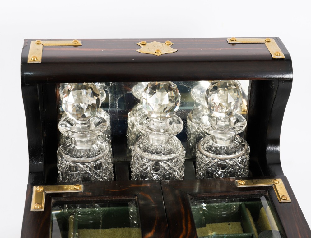 A nineteenth-century coromandel wood scent bottle casket with brass mounts opening to reveal cut-glass bottles and mirrored compartments. View V