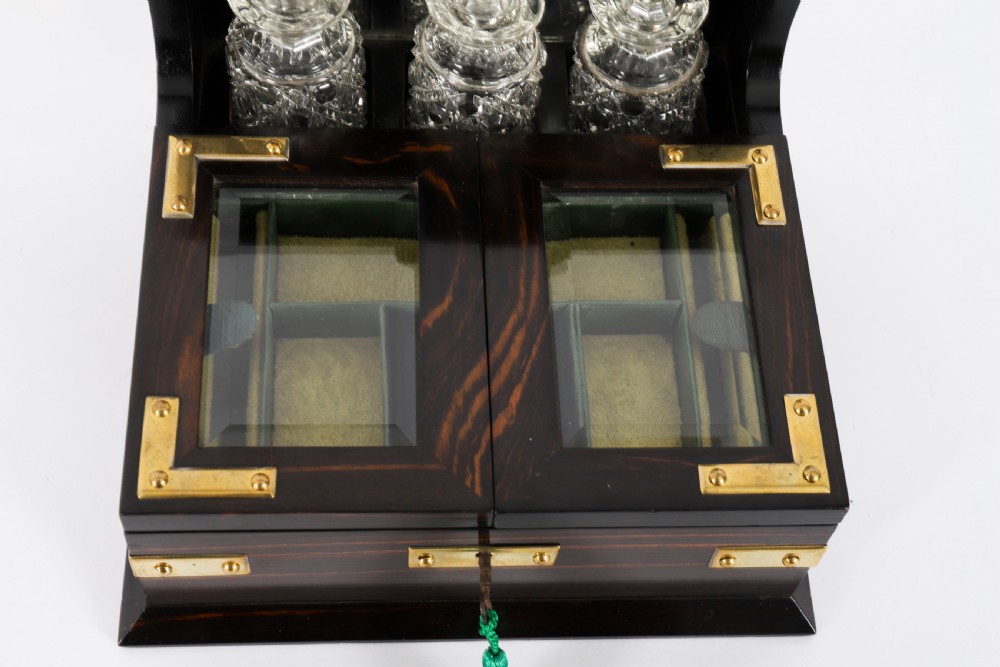 A nineteenth-century coromandel wood scent bottle casket with brass mounts opening to reveal cut-glass bottles and mirrored compartments. View VII
