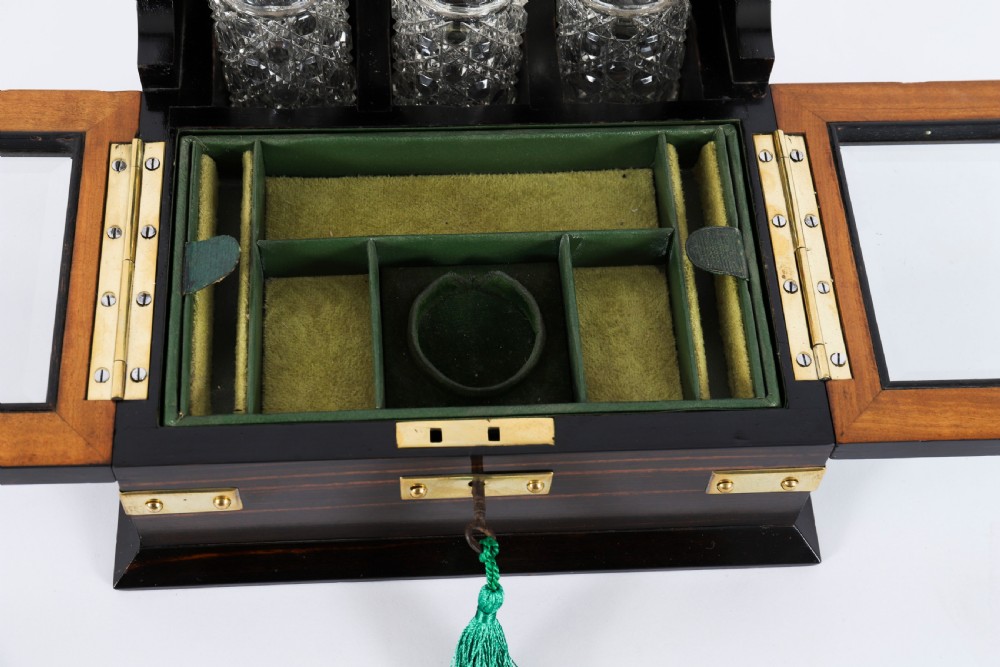 A nineteenth-century coromandel wood scent bottle casket with brass mounts opening to reveal cut-glass bottles and mirrored compartments. View XI