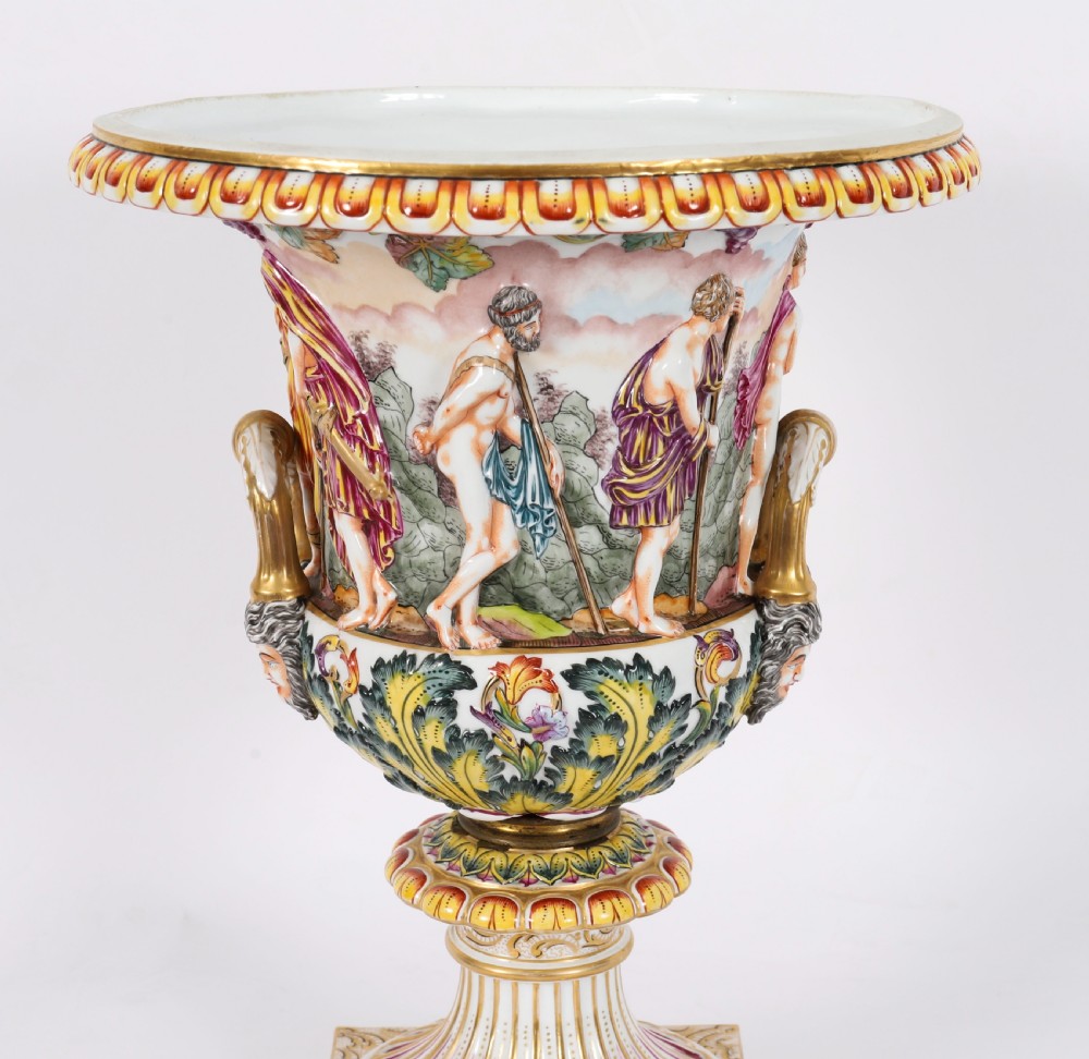 A 19th-century Capodimonte porcelain urn featuring classical figures in high relief, polychrome enamelling, gilded handles, and a square base. View IV