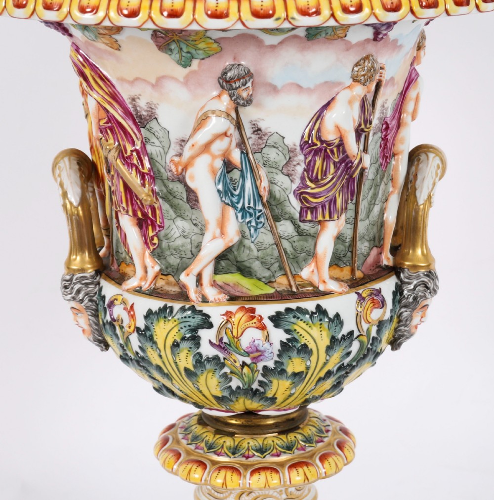 A 19th-century Capodimonte porcelain urn featuring classical figures in high relief, polychrome enamelling, gilded handles, and a square base. View V