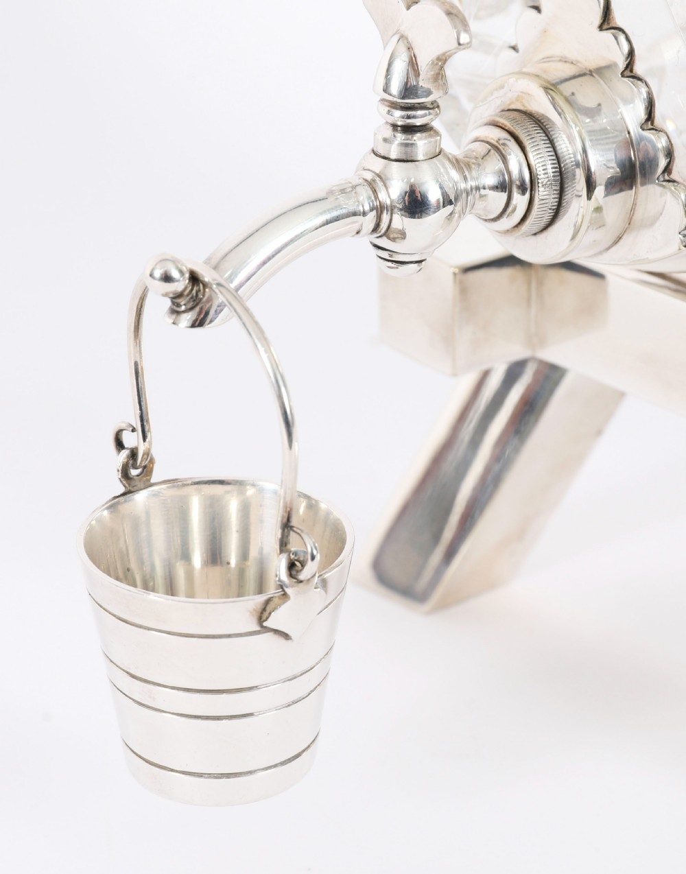 A nineteenth-century cut crystal barrel decanter with silver-plated hoops, tap, and miniature bucket accessory resting on a four-legged silver stand. View II