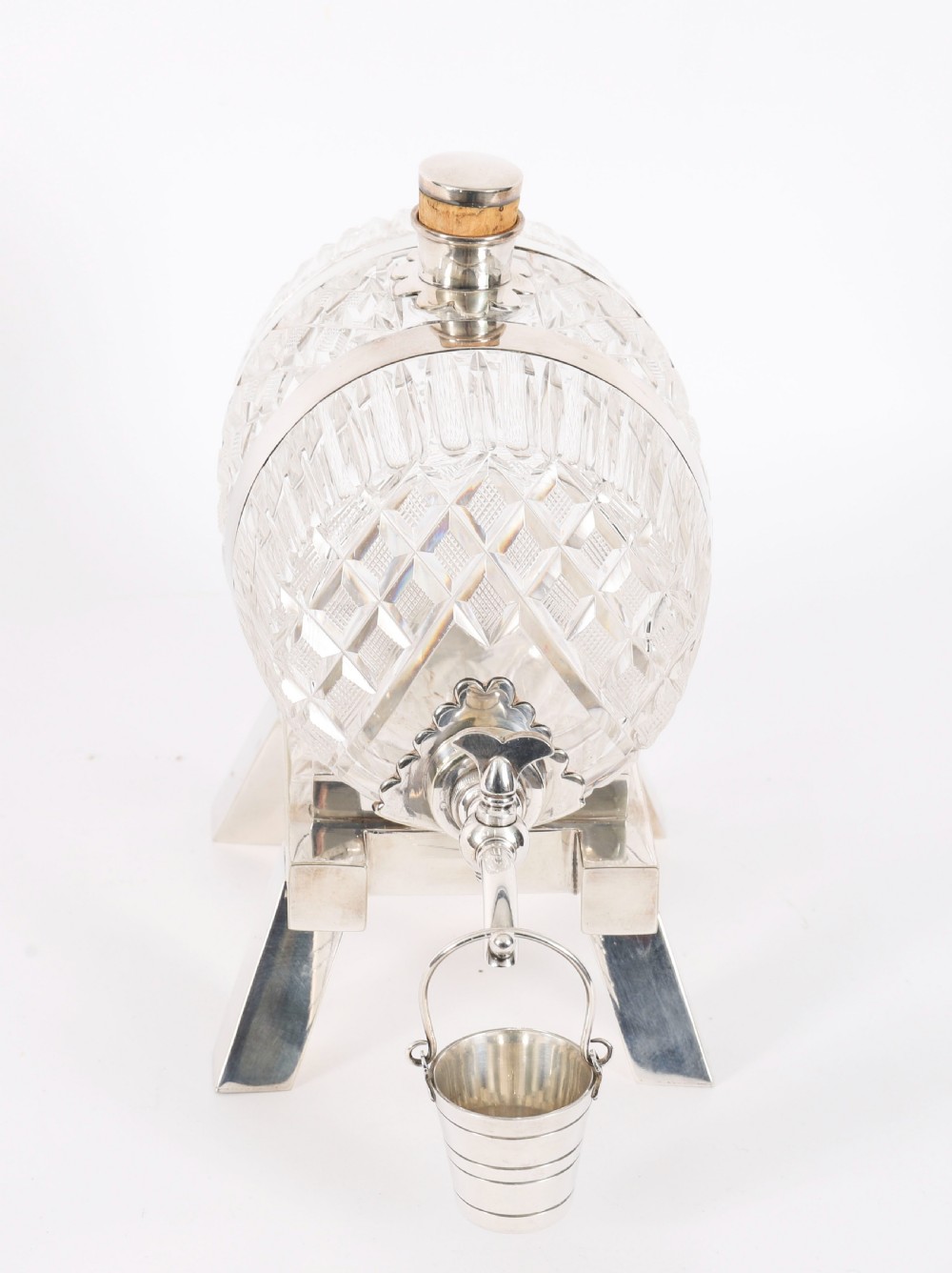 A nineteenth-century cut crystal barrel decanter with silver-plated hoops, tap, and miniature bucket accessory resting on a four-legged silver stand. View IV
