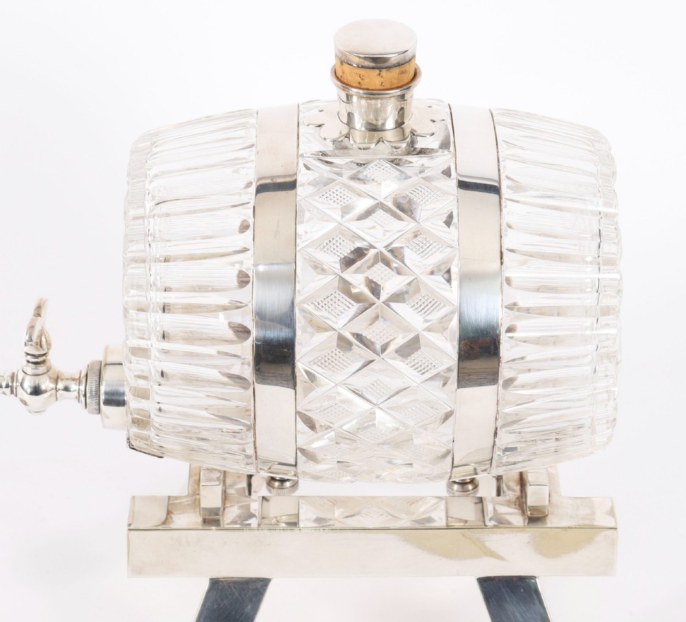 A nineteenth-century cut crystal barrel decanter with silver-plated hoops, tap, and miniature bucket accessory resting on a four-legged silver stand. View IX