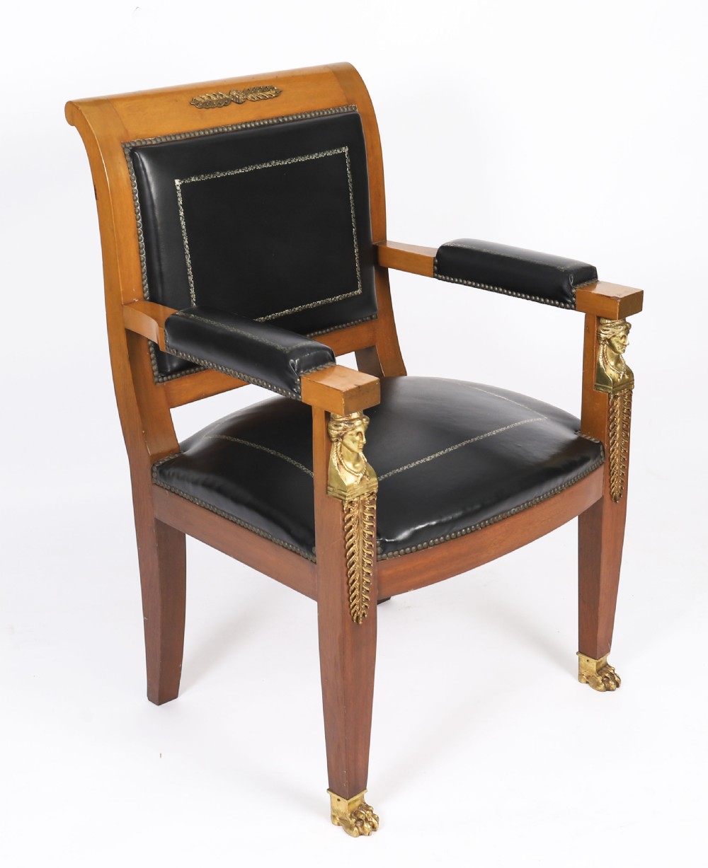 A nineteenth-century French Empire desk chair with black leather upholstery, mahogany frame, and gilt-bronze caryatid mounts.