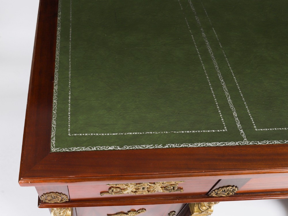 A French Empire style mahogany pedestal desk featuring a green leather top insert, decorative gilt-bronze mounts, and caryatid corner supports. View II