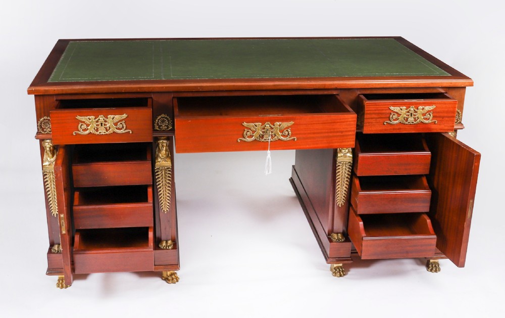 A French Empire style mahogany pedestal desk featuring a green leather top insert, decorative gilt-bronze mounts, and caryatid corner supports. View VI