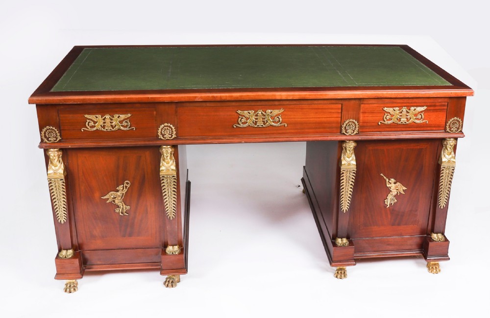 A French Empire style mahogany pedestal desk featuring a green leather top insert, decorative gilt-bronze mounts, and caryatid corner supports. View X