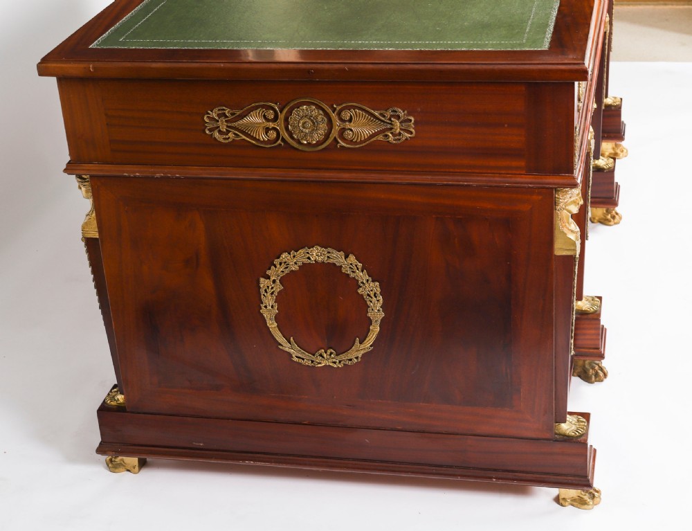 A French Empire style mahogany pedestal desk featuring a green leather top insert, decorative gilt-bronze mounts, and caryatid corner supports. View XIX