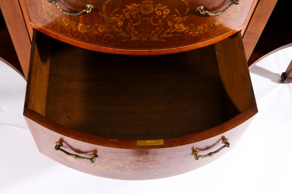 A 19th-century mahogany serpentine display cabinet featuring intricate floral marquetry inlays, three glazed upper doors, three central drawers, and tapered legs. View VIII