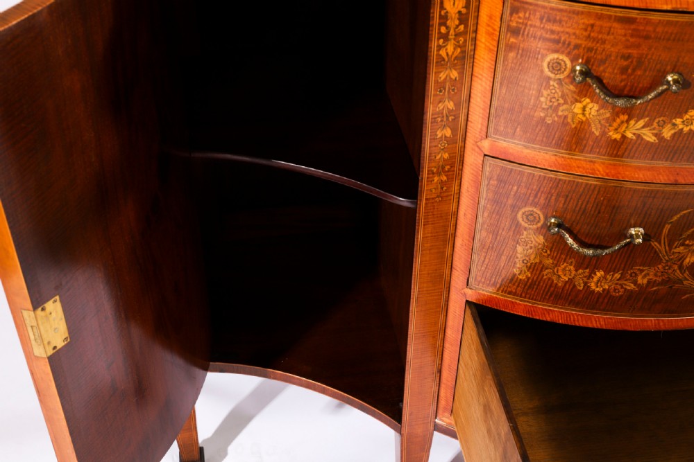 A 19th-century mahogany serpentine display cabinet featuring intricate floral marquetry inlays, three glazed upper doors, three central drawers, and tapered legs. View IX