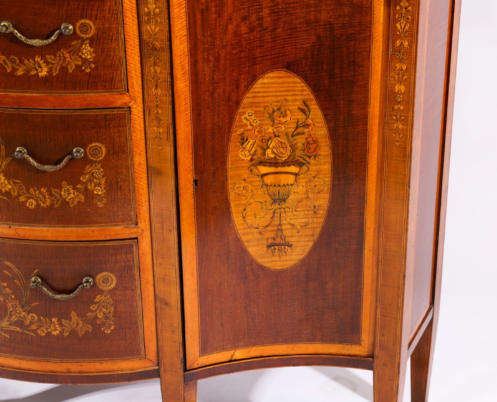 A 19th-century mahogany serpentine display cabinet featuring intricate floral marquetry inlays, three glazed upper doors, three central drawers, and tapered legs. View XIII