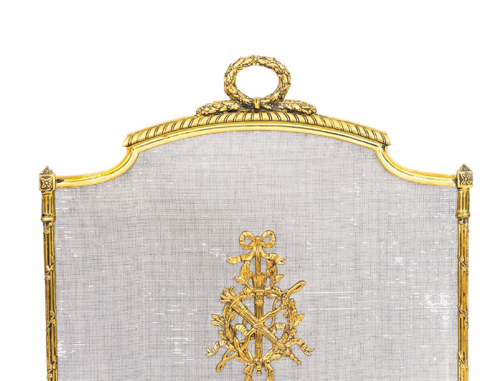 A French Empire Revival gilt bronze fire screen featuring a woven mesh panel, laurel wreath top handle, and central flaming torch motif on splayed feet. View II