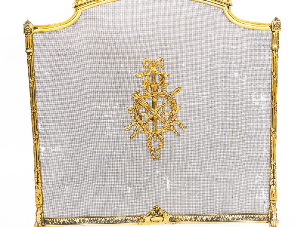 A French Empire Revival gilt bronze fire screen featuring a woven mesh panel, laurel wreath top handle, and central flaming torch motif on splayed feet. View V