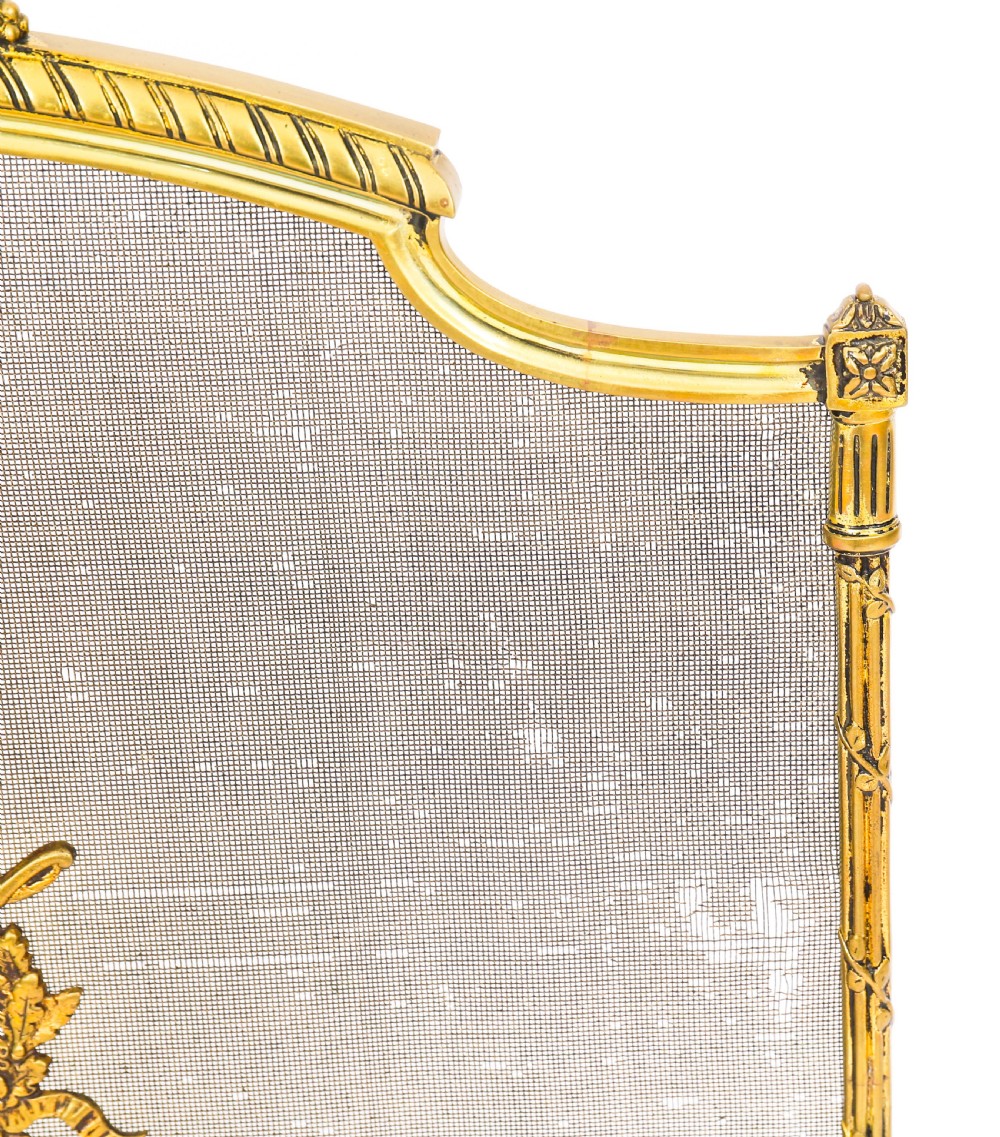 A French Empire Revival gilt bronze fire screen featuring a woven mesh panel, laurel wreath top handle, and central flaming torch motif on splayed feet. View IX