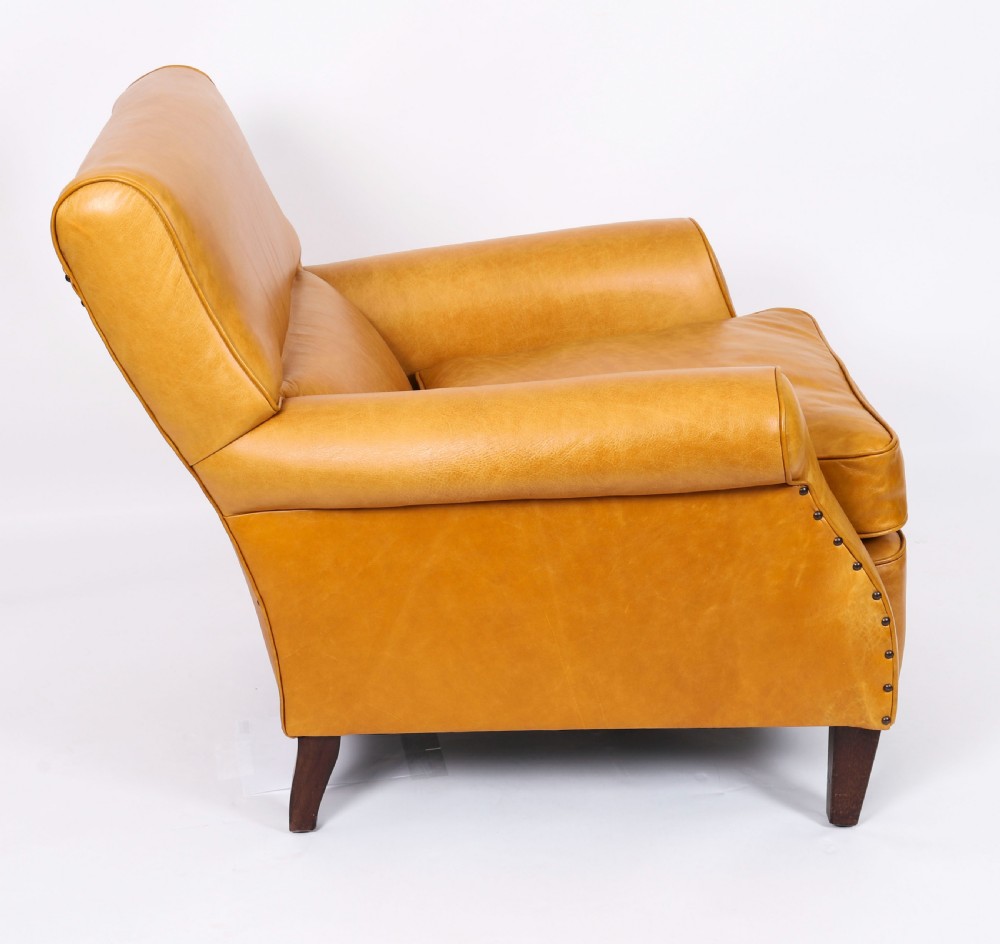 An Art Deco leather armchair upholstered in caramel tan hide with studded trim and square tapered wooden legs. View II