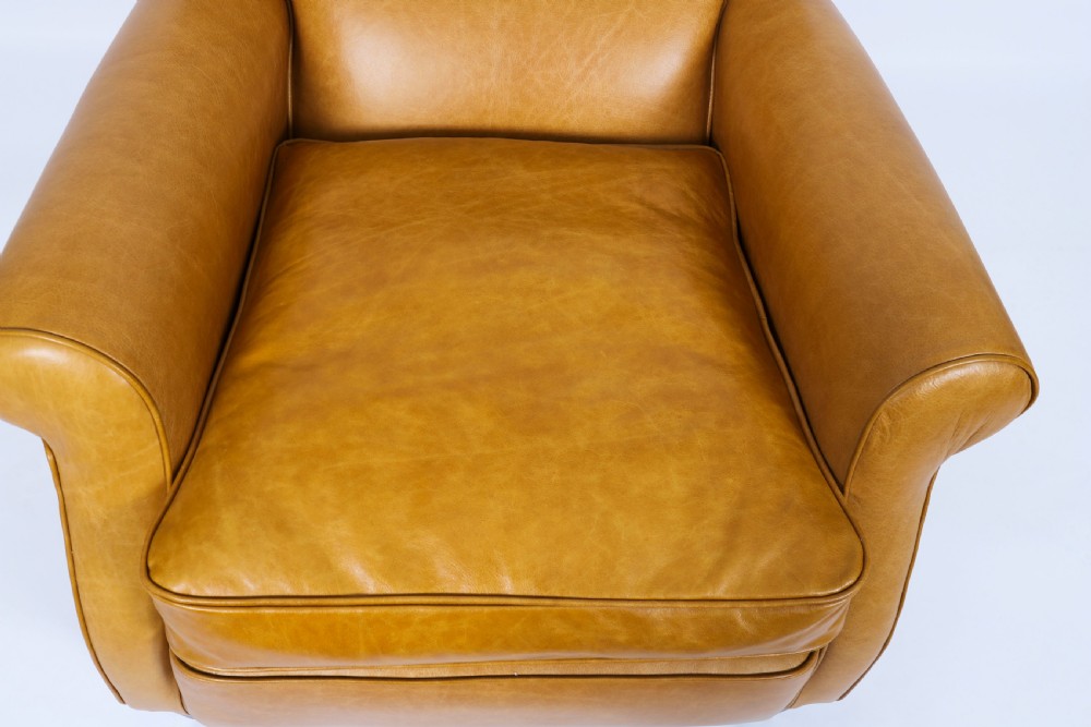 An Art Deco leather armchair upholstered in caramel tan hide with studded trim and square tapered wooden legs. View IV