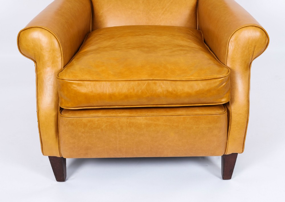 An Art Deco leather armchair upholstered in caramel tan hide with studded trim and square tapered wooden legs. View V