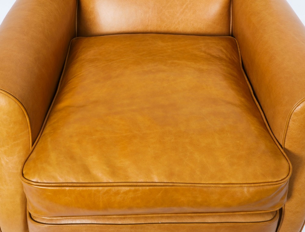 An Art Deco leather armchair upholstered in caramel tan hide with studded trim and square tapered wooden legs. View VI