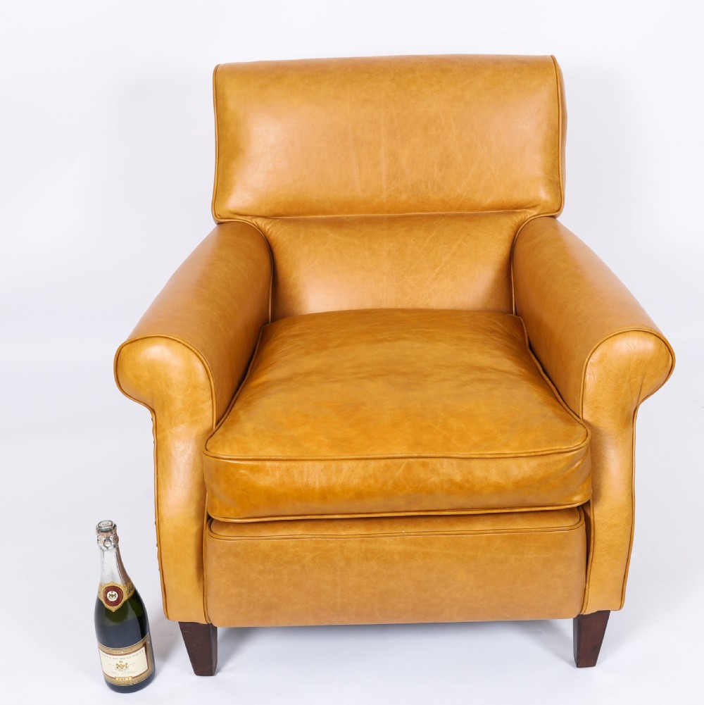 An Art Deco leather armchair upholstered in caramel tan hide with studded trim and square tapered wooden legs. View IX
