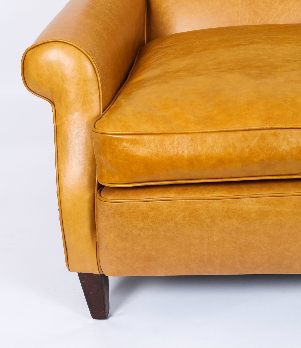 An Art Deco leather armchair upholstered in caramel tan hide with studded trim and square tapered wooden legs. View XII