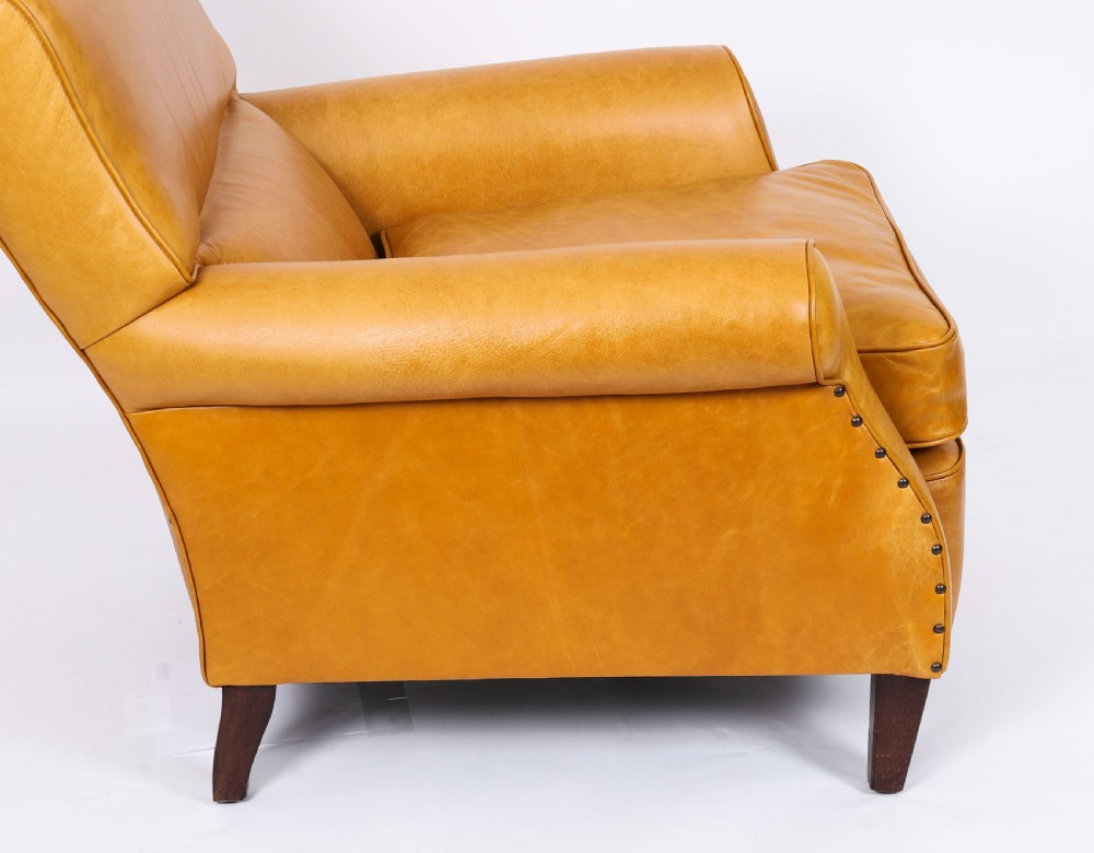 An Art Deco leather armchair upholstered in caramel tan hide with studded trim and square tapered wooden legs. View XIII