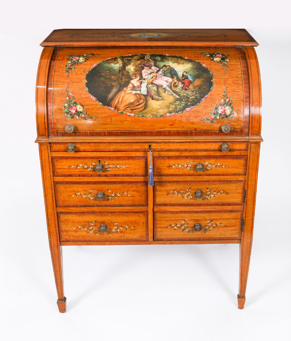 A late Victorian Sheraton Revival satinwood cylinder bureau featuring hand-painted floral swags, a central figural scene, and multiple small drawers above tapered legs. View II