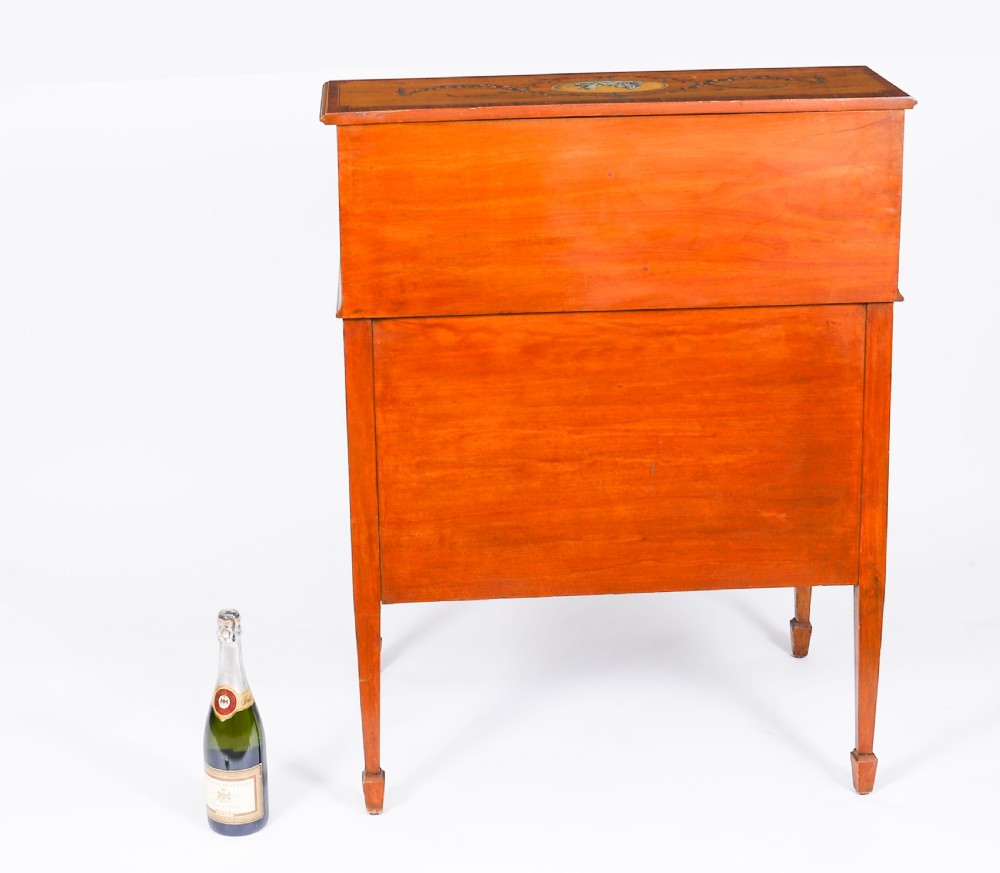 A late Victorian Sheraton Revival satinwood cylinder bureau featuring hand-painted floral swags, a central figural scene, and multiple small drawers above tapered legs. View XII