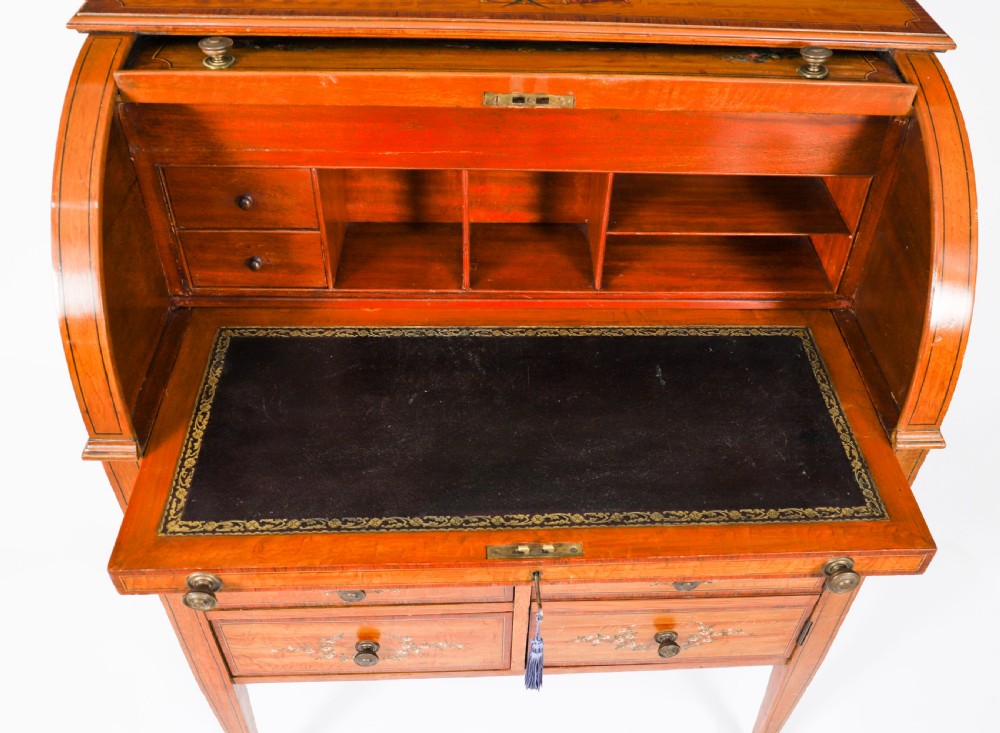A late Victorian Sheraton Revival satinwood cylinder bureau featuring hand-painted floral swags, a central figural scene, and multiple small drawers above tapered legs. View XIV