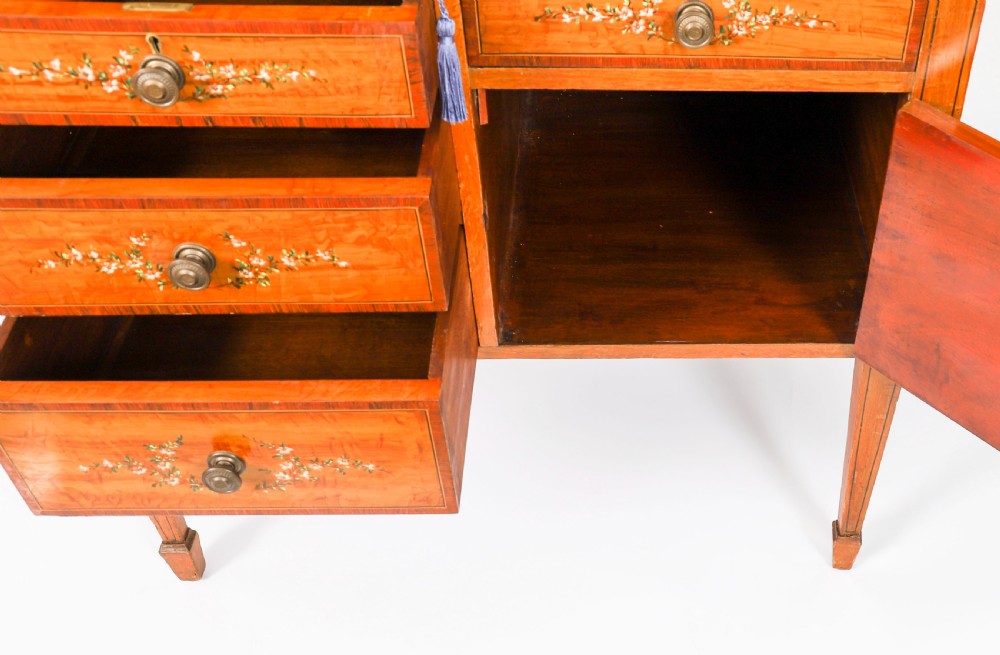 A late Victorian Sheraton Revival satinwood cylinder bureau featuring hand-painted floral swags, a central figural scene, and multiple small drawers above tapered legs. View XVII