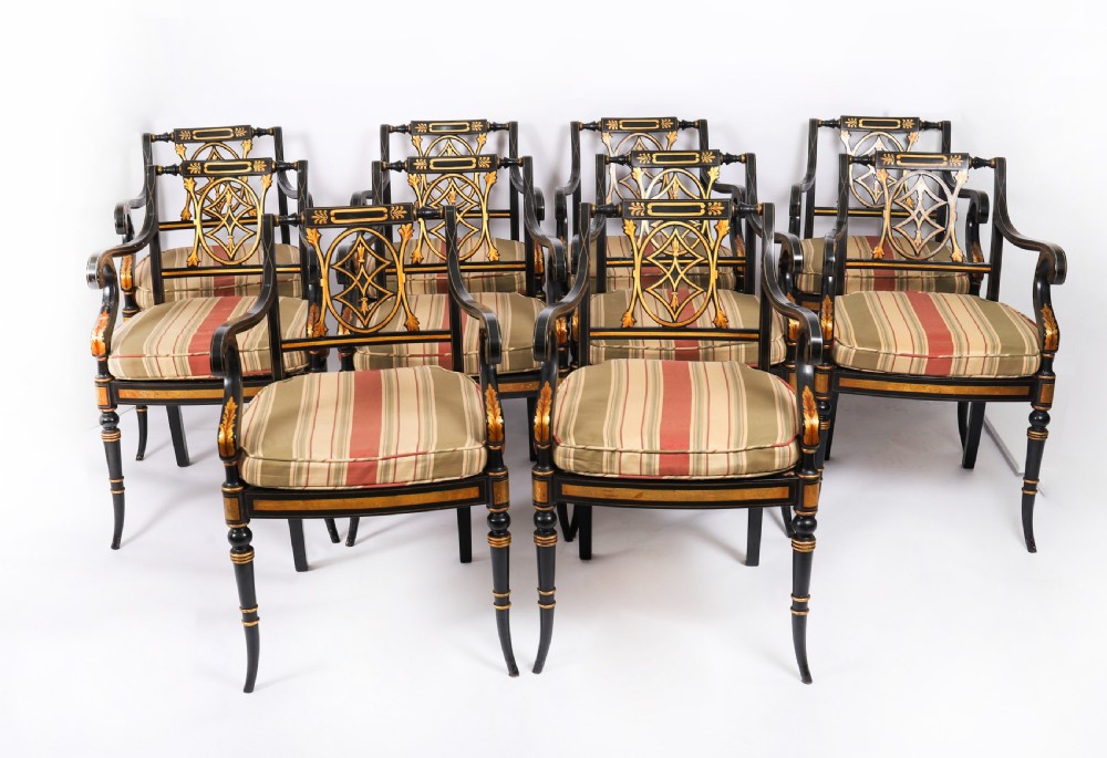 A set of ten ebonised and parcel-gilt Regency Revival dining chairs featuring pierced splat backs and striped upholstered seats.