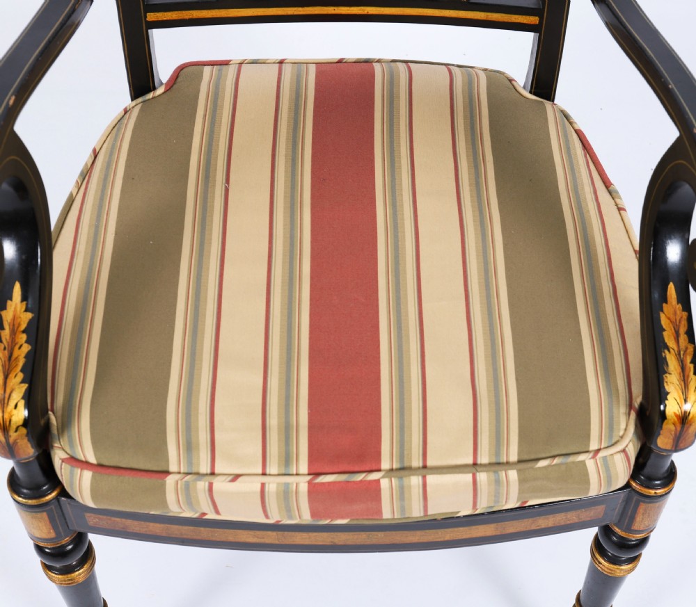 A set of ten ebonised and parcel-gilt Regency Revival dining chairs featuring pierced splat backs and striped upholstered seats. View V