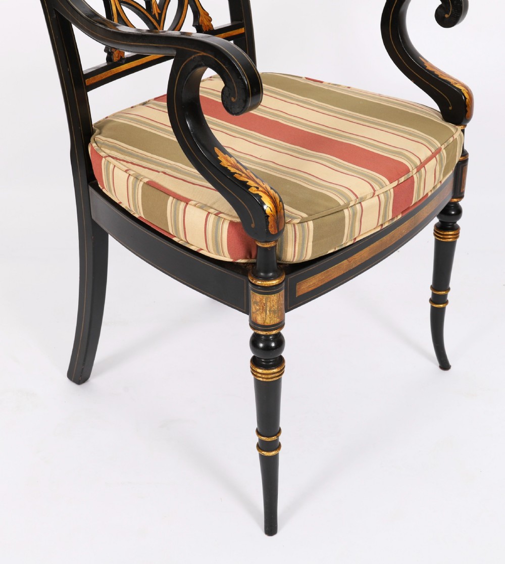 A set of ten ebonised and parcel-gilt Regency Revival dining chairs featuring pierced splat backs and striped upholstered seats. View IX