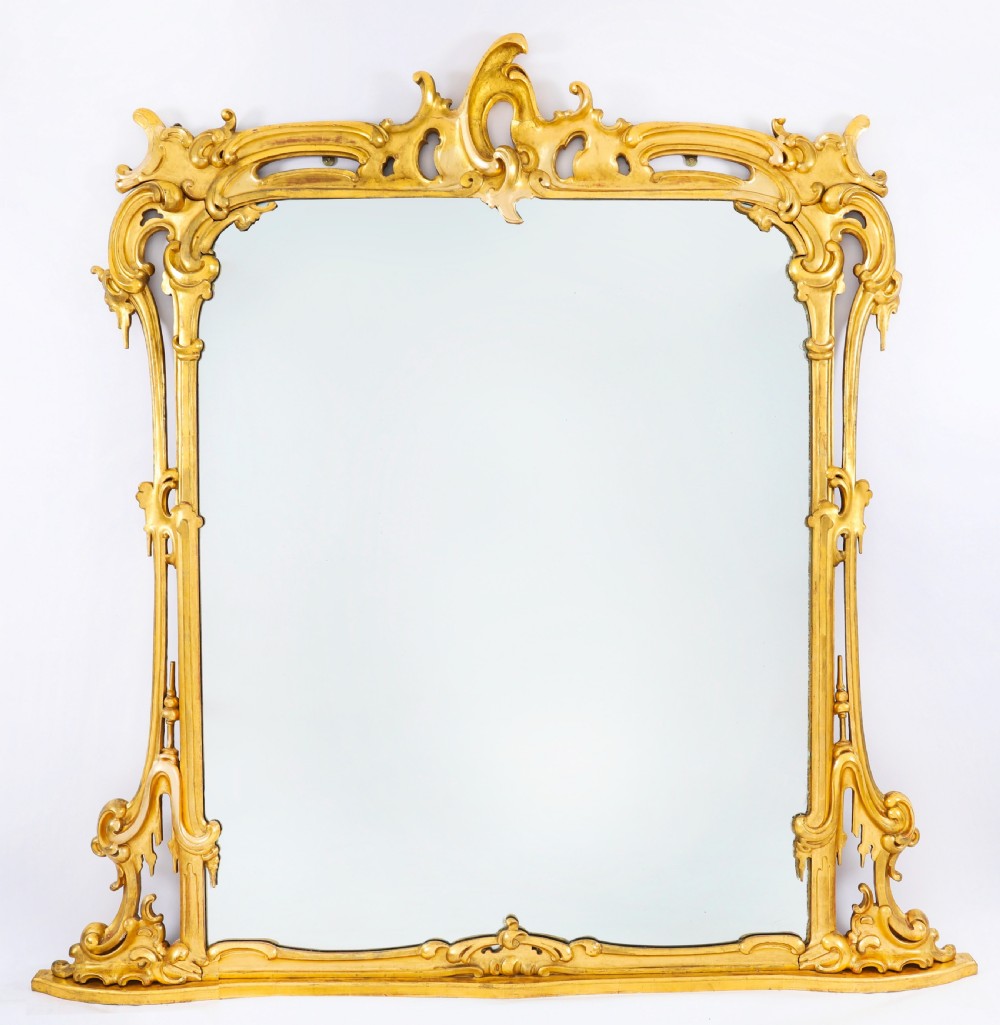 A large 19th-century Rococo Revival giltwood wall mirror featuring a carved frame with C-scrolls and asymmetrical cresting.