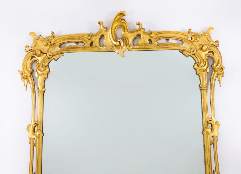 A large 19th-century Rococo Revival giltwood wall mirror featuring a carved frame with C-scrolls and asymmetrical cresting. View IV