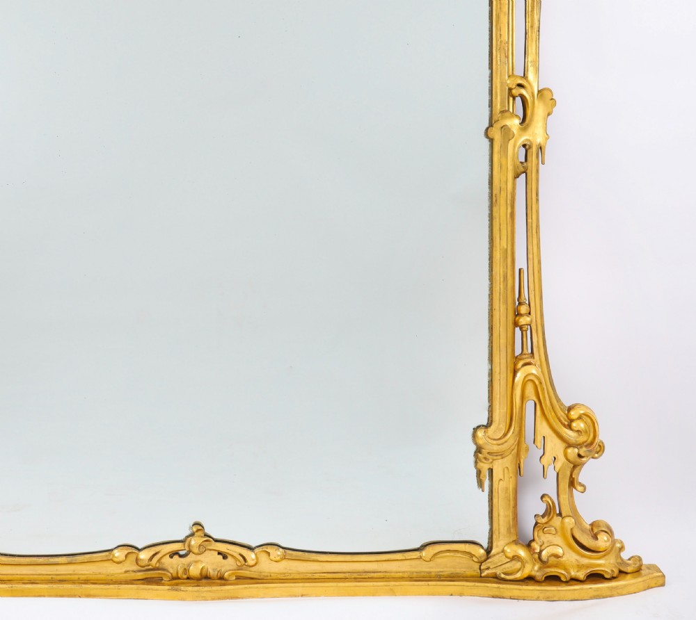 A large 19th-century Rococo Revival giltwood wall mirror featuring a carved frame with C-scrolls and asymmetrical cresting. View VI