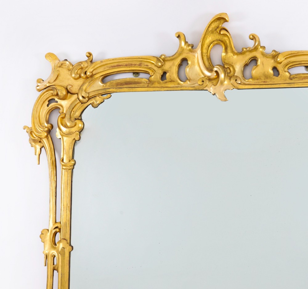 A large 19th-century Rococo Revival giltwood wall mirror featuring a carved frame with C-scrolls and asymmetrical cresting. View VII