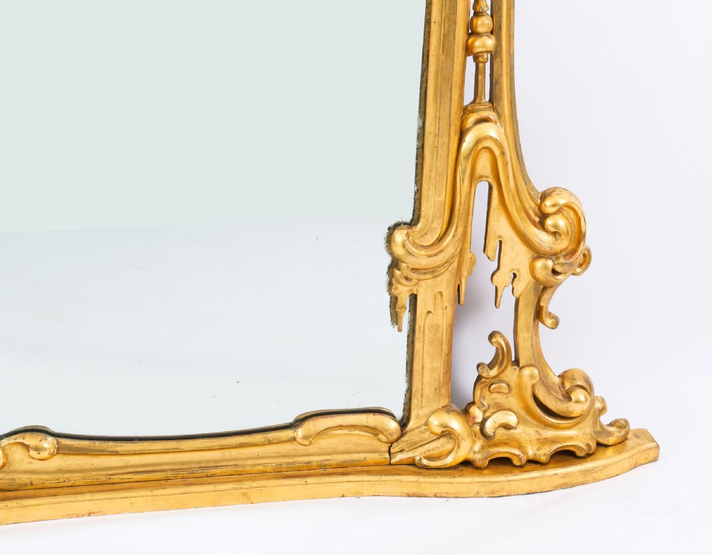 A large 19th-century Rococo Revival giltwood wall mirror featuring a carved frame with C-scrolls and asymmetrical cresting. View VIII