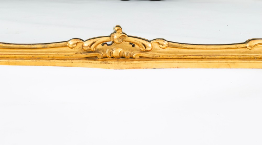 A large 19th-century Rococo Revival giltwood wall mirror featuring a carved frame with C-scrolls and asymmetrical cresting. View XI