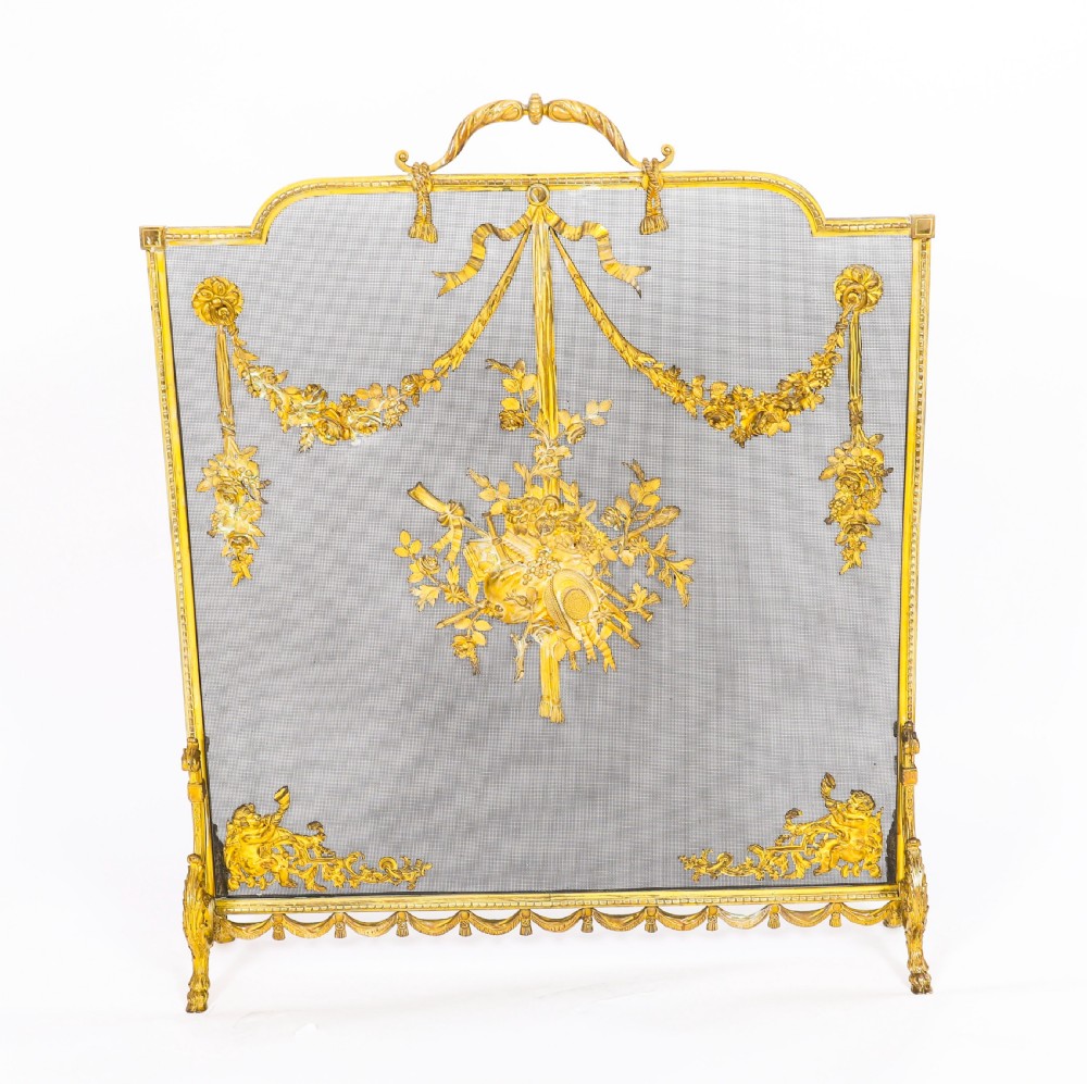 A 19th-century French gilt bronze fire screen featuring a woven mesh panel decorated with central musical trophy motifs, floral garlands, and ribbon swags. View III