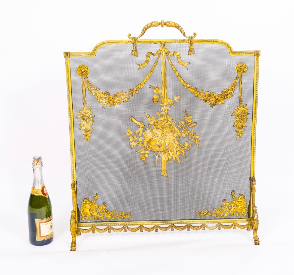 A 19th-century French gilt bronze fire screen featuring a woven mesh panel decorated with central musical trophy motifs, floral garlands, and ribbon swags. View XII