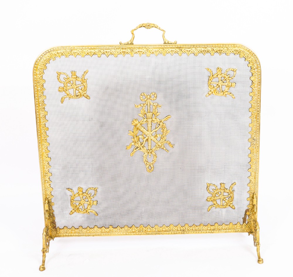 A 19th-century French Empire Revival gilt bronze fire screen featuring fine wire mesh adorned with cast classical trophy mounts, a top handle, and scrolled feet. View II