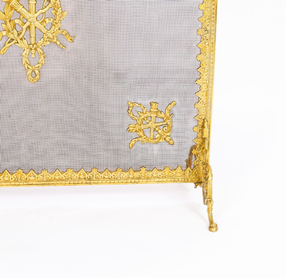 A 19th-century French Empire Revival gilt bronze fire screen featuring fine wire mesh adorned with cast classical trophy mounts, a top handle, and scrolled feet. View IX