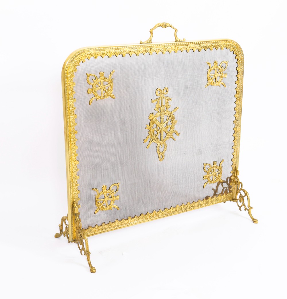 A 19th-century French Empire Revival gilt bronze fire screen featuring fine wire mesh adorned with cast classical trophy mounts, a top handle, and scrolled feet. View XI