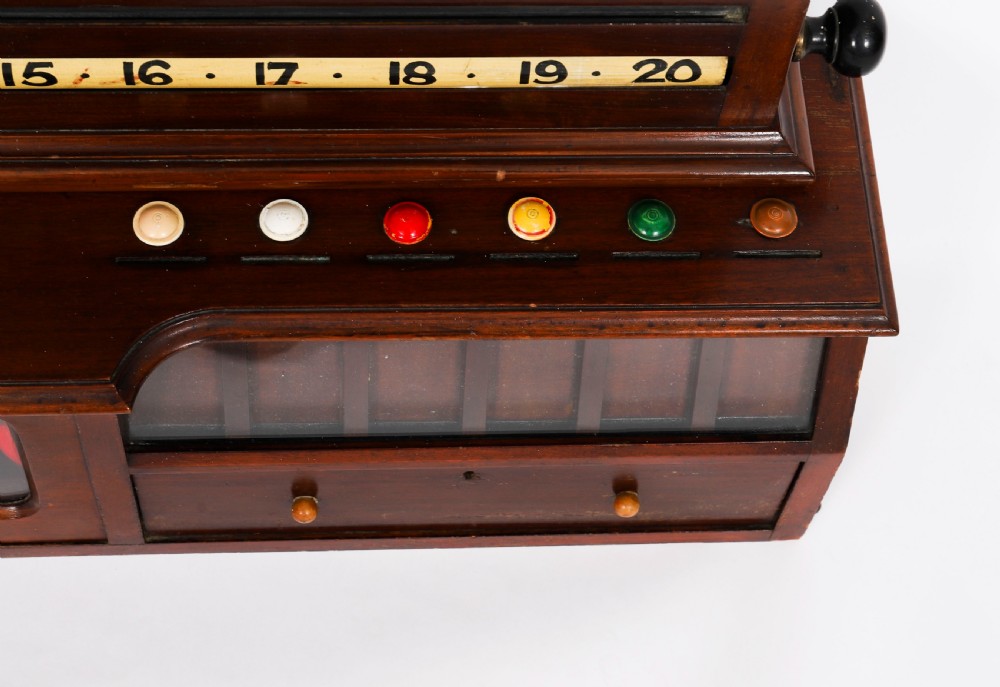 A Victorian mahogany life pool scoreboard featuring a central slate panel, brass slider indicators, coloured markers, and a lower glazed cabinet displaying billiard balls. View VII
