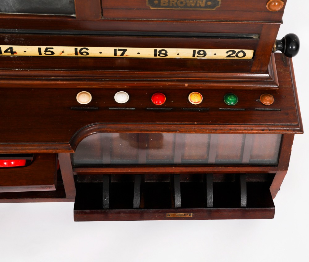 A Victorian mahogany life pool scoreboard featuring a central slate panel, brass slider indicators, coloured markers, and a lower glazed cabinet displaying billiard balls. View XV