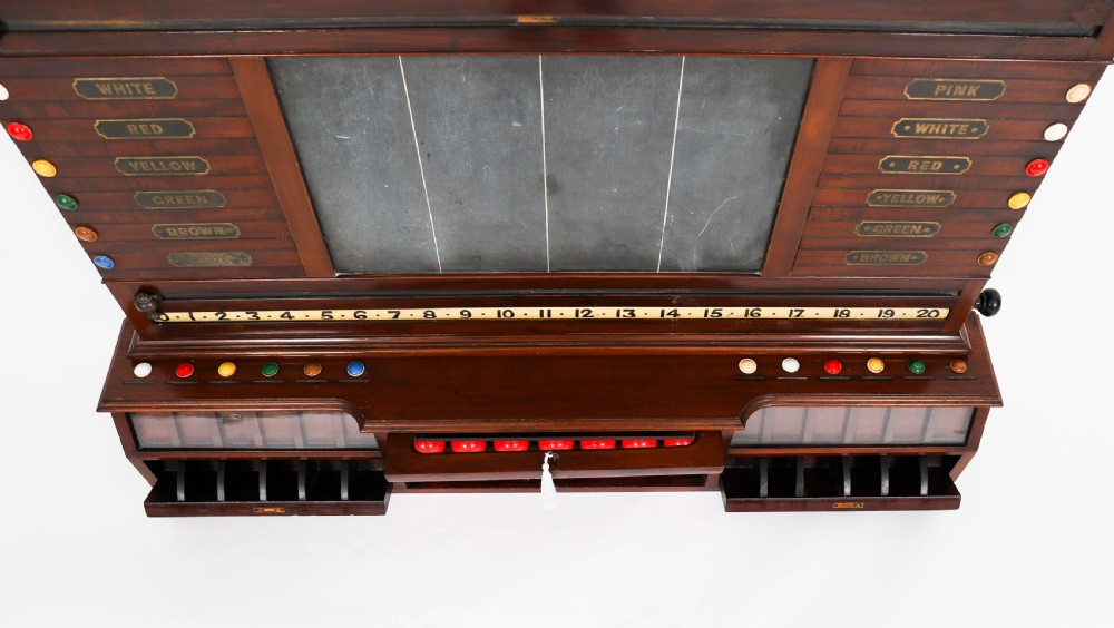 A Victorian mahogany life pool scoreboard featuring a central slate panel, brass slider indicators, coloured markers, and a lower glazed cabinet displaying billiard balls. View XVI