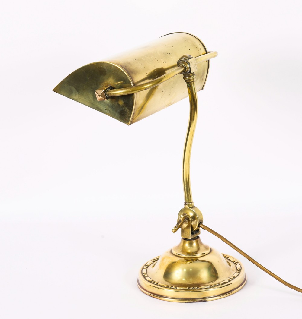 An Art Deco articulated brass desk lamp featuring a curved adjustable arm, a rectangular brass shade, and a moulded circular base. View II