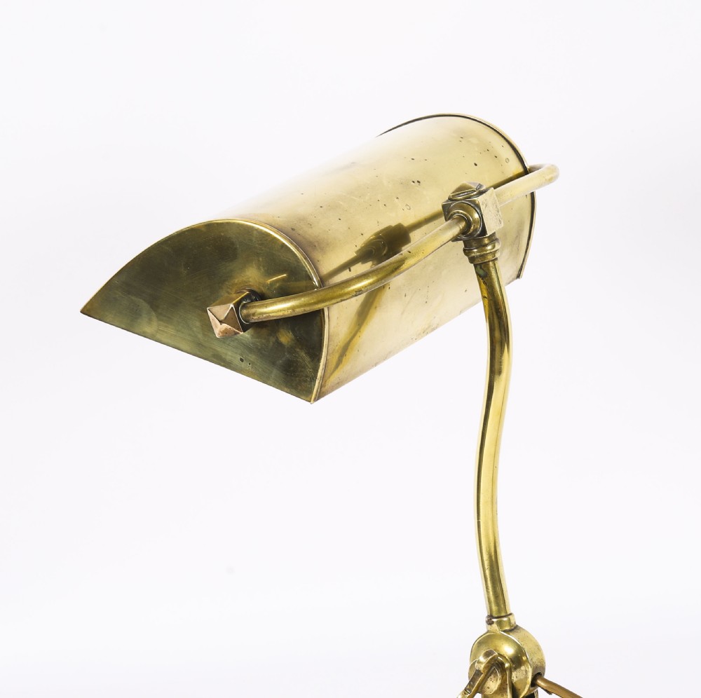 An Art Deco articulated brass desk lamp featuring a curved adjustable arm, a rectangular brass shade, and a moulded circular base. View III