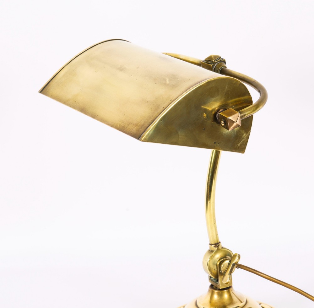 An Art Deco articulated brass desk lamp featuring a curved adjustable arm, a rectangular brass shade, and a moulded circular base. View IV